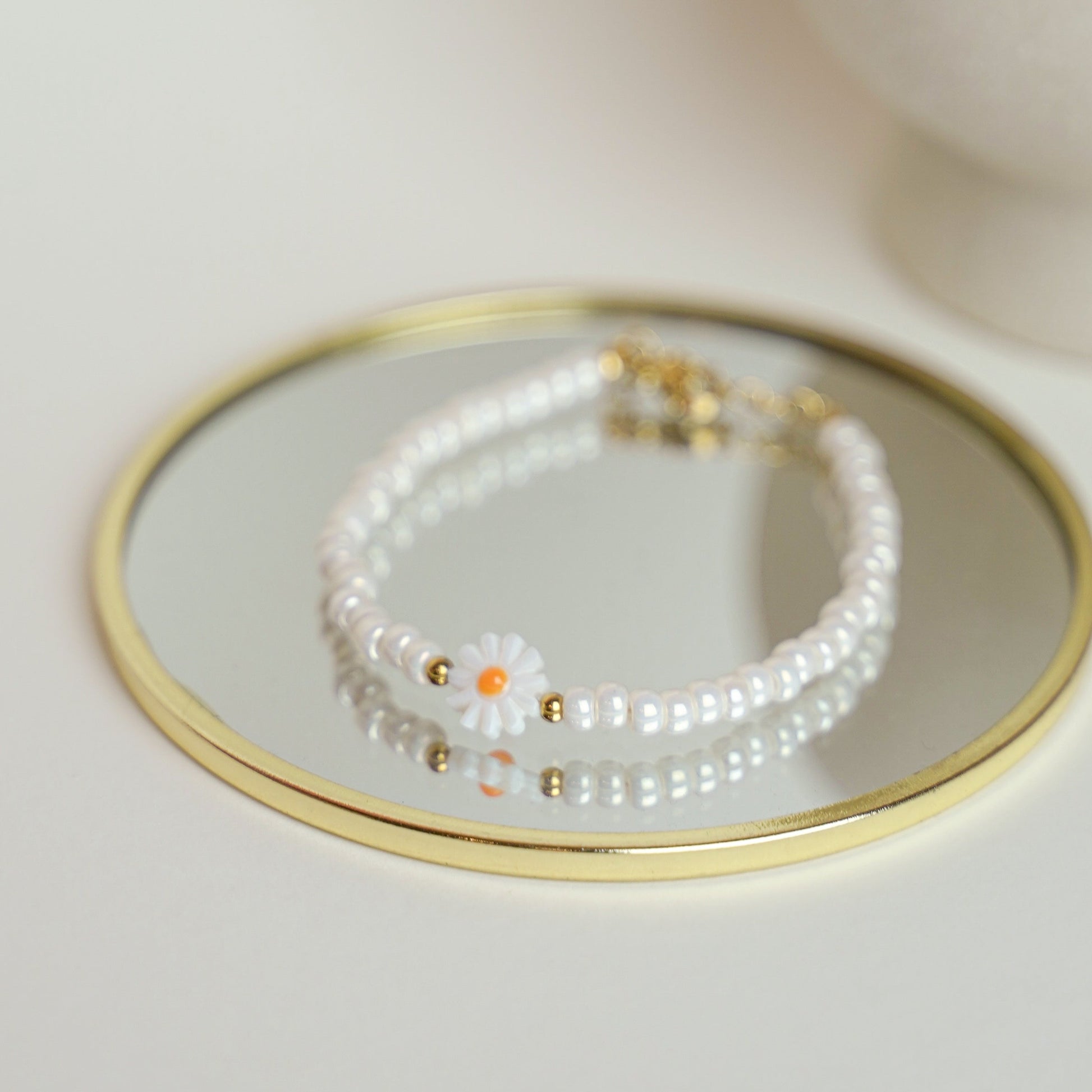 Gänseblümchen-Perlenarmband auf einem Spiegel