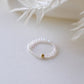 Glasperlenring mit Edelstahlperle auf einem Hellen Hintergrund mit einer Trockenblume